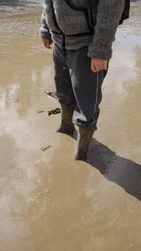 Low section of a person ankle-deep in a muddy puddle Stock Photos