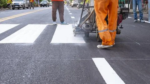 Low section of road workers group with thermoplastic spray marking machine .. Stock Photos