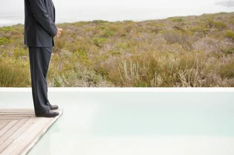 Low section view of a businessman standing on a platform at an infinity pool Stock Photos
