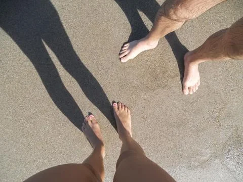 Low section view of a man and women  young couple legs  standing on sand on t Stock Photos