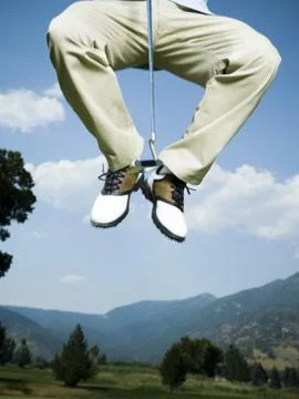 Low section view of a man jumping in air with a golf club Foto stock