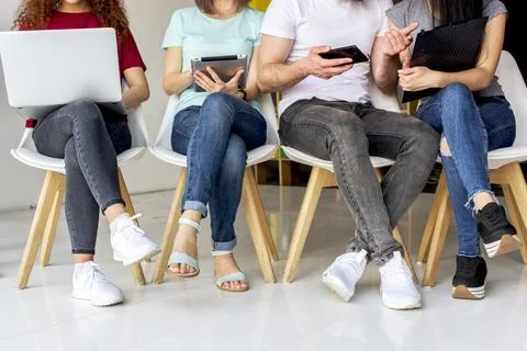 Low section view people sitting chair using wireless devices 写真素材