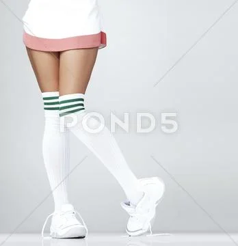 Low Section Of Woman Wearing Sneakers And Knee-High Socks