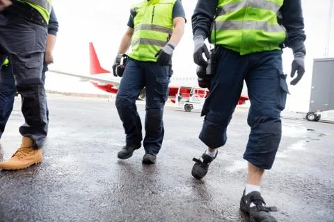 Low Section Of Workers Walking On Wet Runway Stock Photos