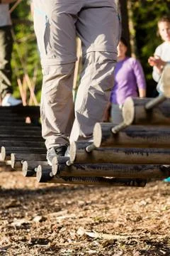 Low Section Of Young Man Crossing Log Bridge In Forest 写真素材