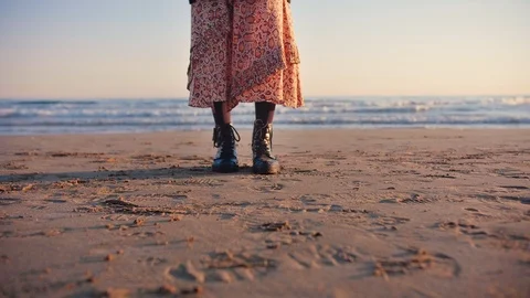 Low shot legs of a stylish dressed woman in vintage outfit standing on a beach Stock Footage 105599524