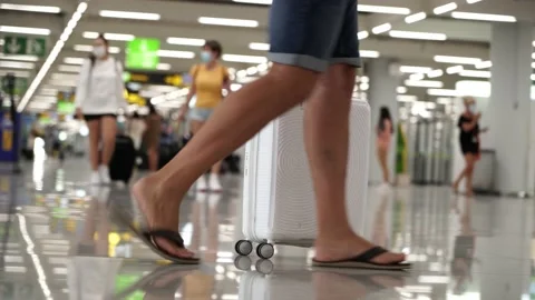 Low shot of a man walking through the airport terminal carrying a bag and unr Stock Footage 136393573