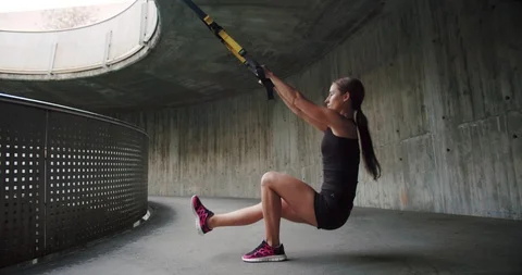 Low side shot of purposeful Caucasian female using TRX holding loops training Stock Footage 123662086