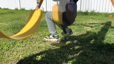Low side shot of young boy swinging on a swing set Stock-Footage 129467889