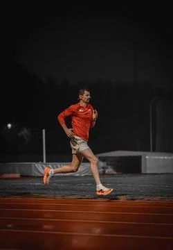 Low side view of a runner on a red track at night 写真素材
