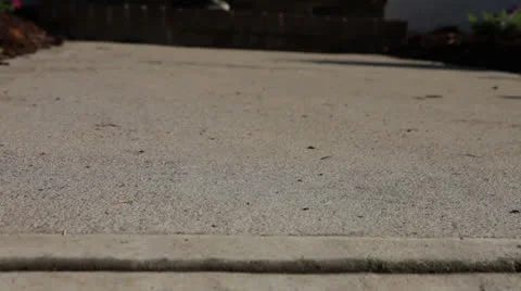 Low Sidewalk, kid skating past with mom following, shallow focus, static Stock Footage 26136500