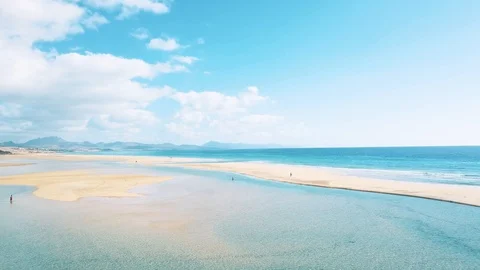 Low sideway aerial flight revealing perspective of groups of people on the beach Stock Footage 127992653