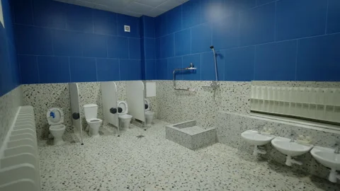 Low sinks stand beside shower platform and small toilets Stock Footage 334141087