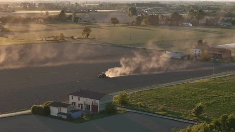 Low slow-motion parallax orbit of tractor raising dust across Po Valley Vídeo Stock 340383856