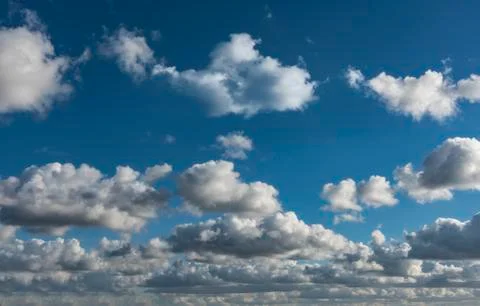 Low small compact and vivid white clouds against a blue gradient sky backgrou Фото