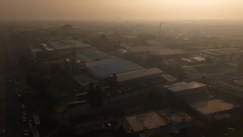 The low sun angle casts deep shadow across the vast roofs of manufacturing Vidéo 334194372