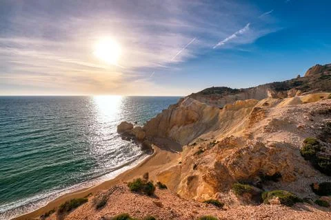 Low sun over beach, cliffs and hills and deep azure sea. Agios Ioannis beach Stock Photos