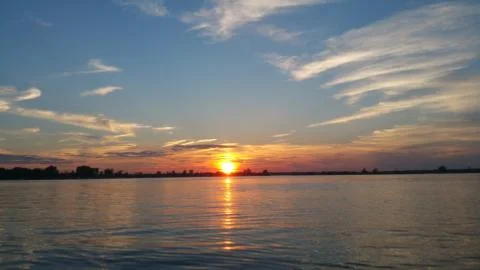 Low sunset in between the clouds reflecting off the lake Foto stock