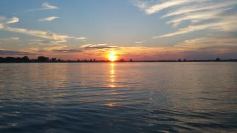 Low sunset in between the clouds reflecting off the lake Foto stock