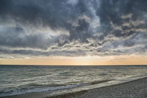 Low thunderclouds float above the sea revealing a sunset view Stock Photos