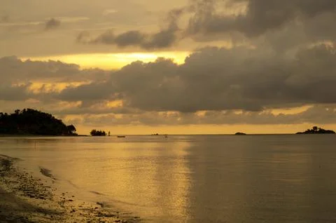 Low tide beach scene illuminated by a golden sunset casting warm reflection.. Stock Photos