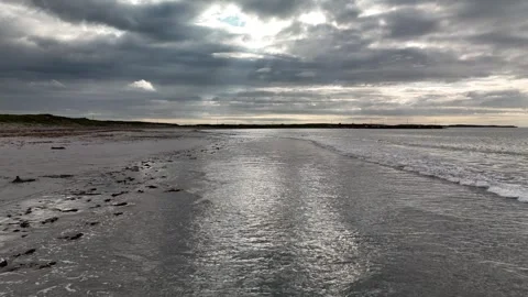Low tide beach with seaweed and waves under dramatic cloudy sky Stock Footage 332679995