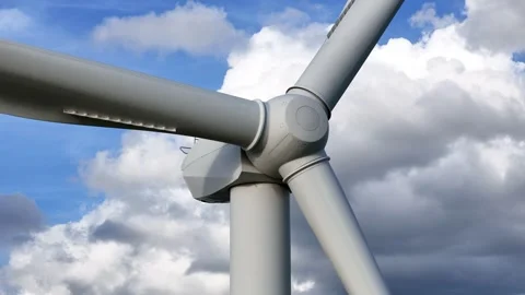 Low towering wind turbine three elongated blades cutting across blue sky rolling Stock Footage 329093367