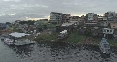 Low tracking aerial along Amazon River past wooden riverboats with poor 스톡 동영상 101291140