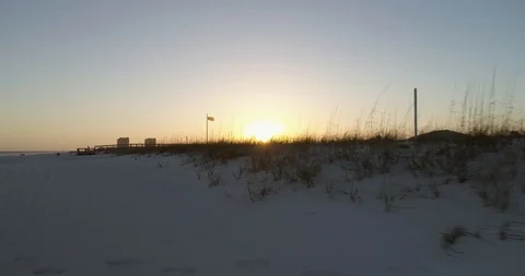 Low tracking shot along grass and beach shows lifeguard flag drone aerial 4K Stock Footage 111415996