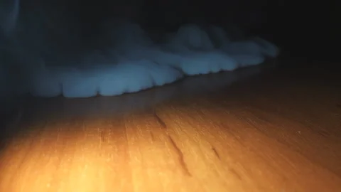 Low view of heavy white smoke from the vape spreading on the surface of table Video stock 329620970