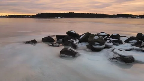 Low view of ice and rocks in the sea at colorful sunset in the winter Stock Footage 148272892