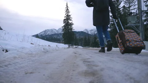 Low view of unrecognizable man walks on trail and pulling suitcase on wheels Video stock 135119906
