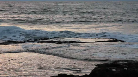 Low waves breaking on a rock shelves during sunset. Stock Footage 34133936