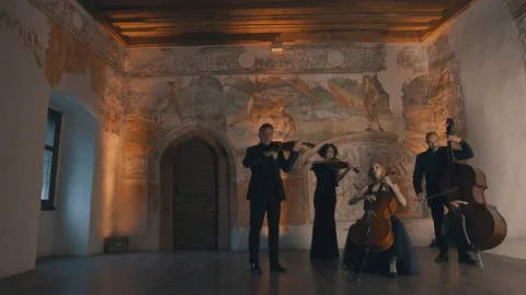 Low wide angle shot of a string quartet playing slowly in a medeival style Vídeo Stock 92504103