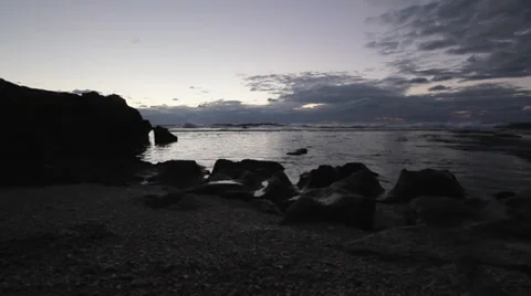 Low, Wide angle shot of waves breaking on a rocky shoreline during sunset Stock Footage 34134203