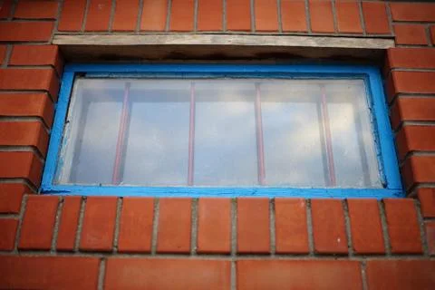 Low window with blue frame and iron grating in a brick building Stock Photos