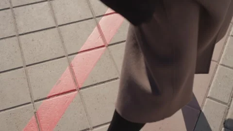 Lowangle footsteps near red stripe, coat hem and takeaway cup, quick pace Stock Footage 331730520