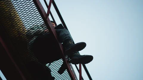 Lowangle shot of hanging climber and textured steel, Dramatic perspective Stock Footage 327759619