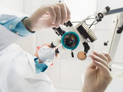 Lowe angle view of dentist using microscope Stock Photos