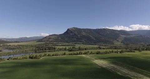 Lower angle drone panning shot of jagged mountain in rural farmland - Enderby Stock Footage 93423627