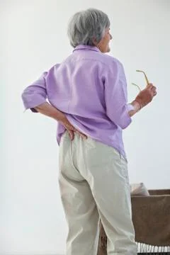 Lower back pain in elderly pers. Stock Photos