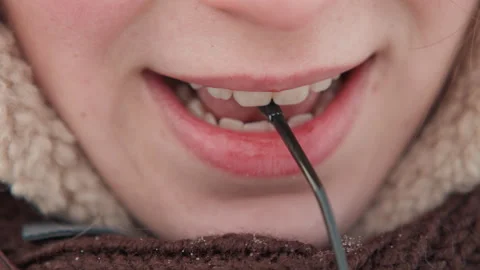 Lower face biting thin cable while wearing fleece collared winter jacket, lips Stock Footage 345656785