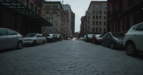 Lower Manhattan low to the ground middle of cobblestone street at dusk Stock Footage 217921386
