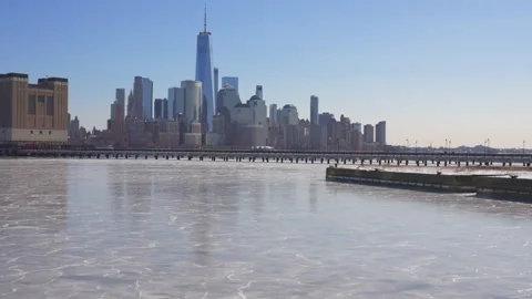 Lower Manhattan skyscraper stands beyond frozen Hudson River from New Jersey. 스톡 동영상 336574426