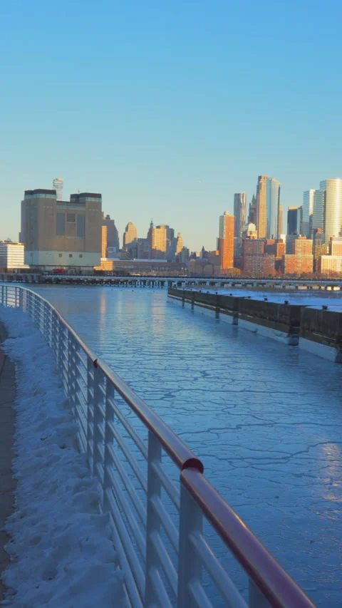 Lower Manhattan skyscraper stands beyond frozen Hudson River in dusk. 動画素材 336634859