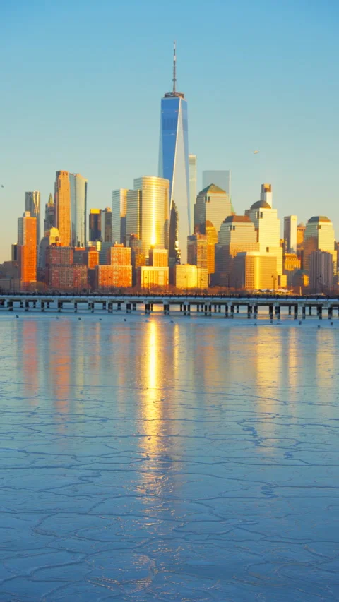 Lower Manhattan skyscraper stands beyond frozen Hudson River in dusk. Vídeo Stock 336640012