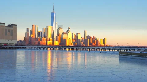 Lower Manhattan skyscraper stands beyond frozen Hudson River in dusk. Vídeo Stock 336642663