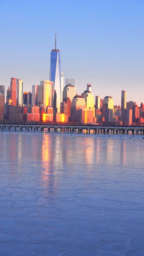 Lower Manhattan skyscraper stands beyond frozen Hudson River in dusk. 動画素材 336643764