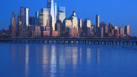 Lower Manhattan skyscraper stands beyond frozen Hudson River in dusk. Vídeo Stock 336650324