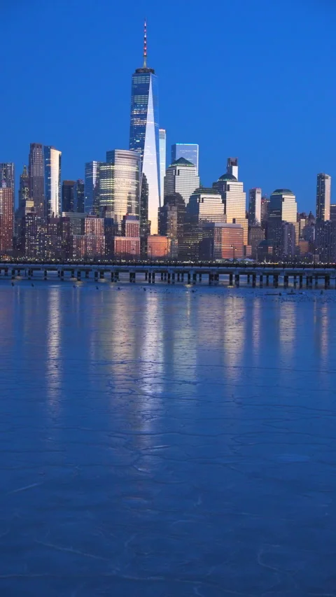 Lower Manhattan skyscraper stands beyond frozen Hudson River in dusk. Vídeos de archivo 336651314